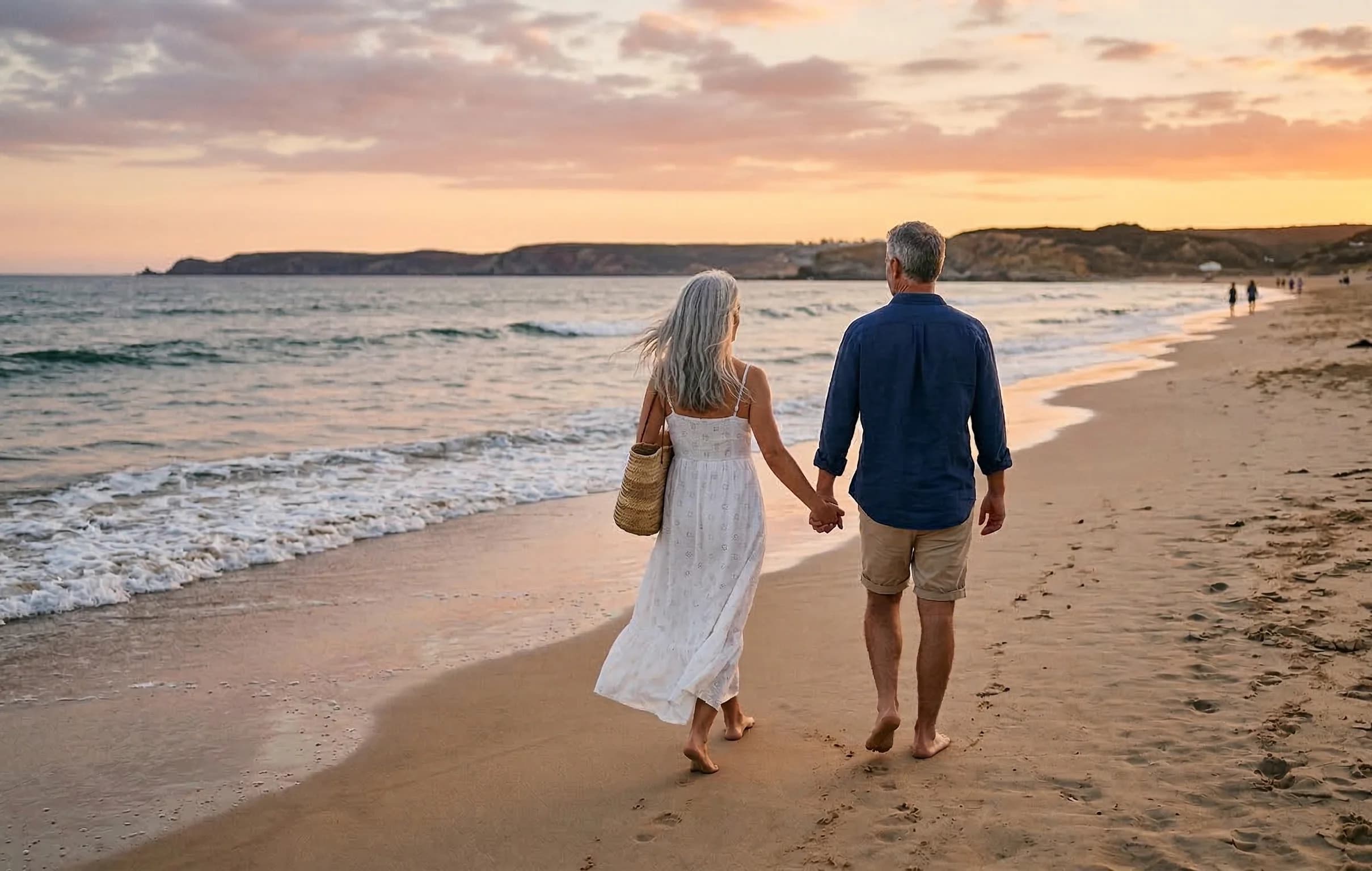 Couple marchant main dans la main sur la plage au coucher du soleil